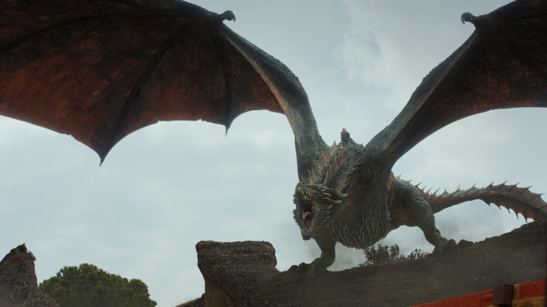 Daenerys riding Drogon landing on a rampart on Game of Thrones