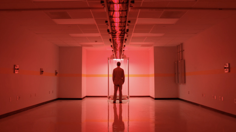 రాబర్ట్ బక్లీ యొక్క ఆడమ్ డైమెన్షన్ 404లోని రెడ్ రూమ్‌లో కెమెరాకు వెనుకవైపు నిలబడి ఉన్నాడు