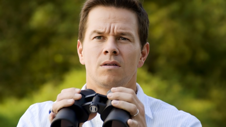 Mark Wahlberg como Elliot Moore sosteniendo binoculares en The Happening