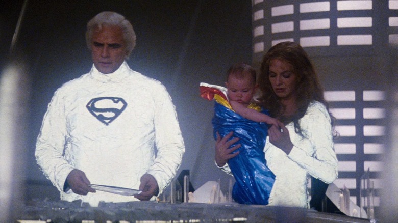 Marlon Brando's Jor-El stands next to Susannah York's Lara as she holds a young Kal-El in Superman