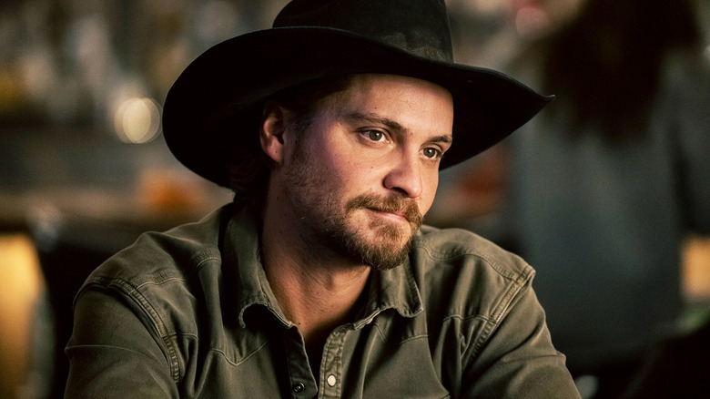 Luke Grimes' Kayce Dutton sits down looking at something off camera in Marshals