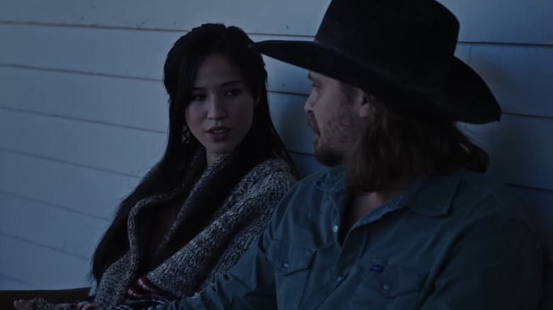 Kelsey Asbille's Monica Dutton looks over at Luke Grimes' Kayce Dutton as they sit side by side outside in Yellowstone