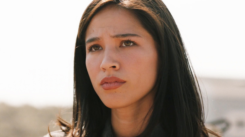 Kelsey Asbille's Monica Dutton looks off into the distance as she stands outside in Yellowstone