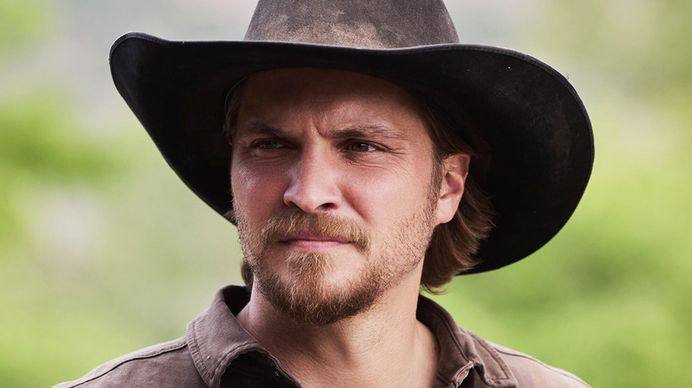 Luke Grimes Kayce Dutton is seen in closeup against a blurry green background in Marshals
