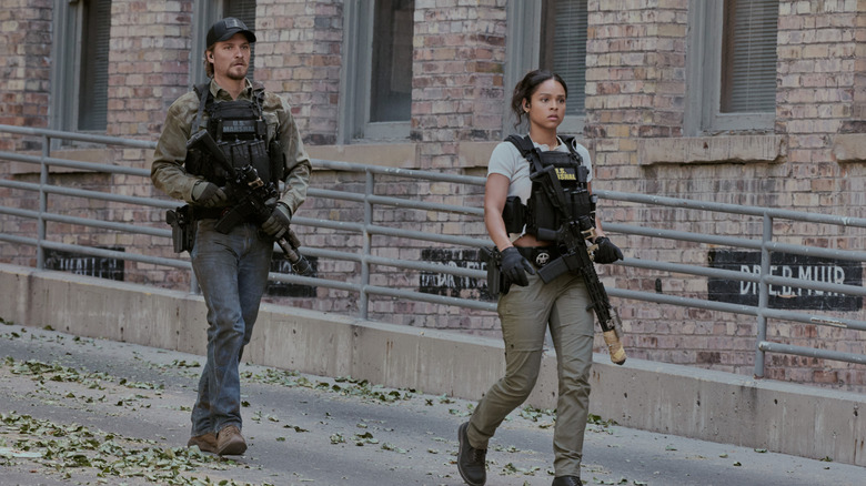 Ash Santos' Andrea Cruz and Luke Grimes' Kayce Dutton walk down a street in their tactical gear in Marshals