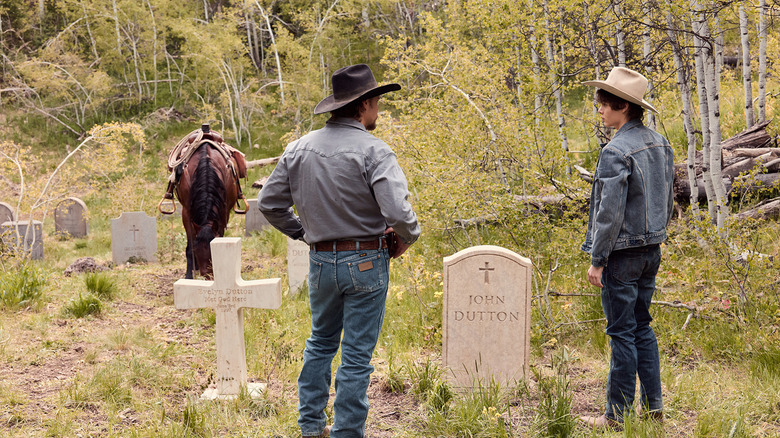 Luke Grimes' Kayce Dutton stands beside Brecken Merrill's Tate Dutton in front of John Dutton's grave in Marshals