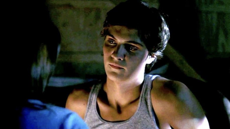 Luke Grimes' Jake stands in a dark room talking to a girl with her back to camera in All the Boys Love Mandy Lane