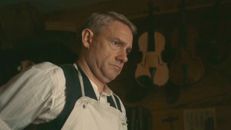 Martin Freeman's Malcolm ties his apron as he looks into the distance in Queen of Bones