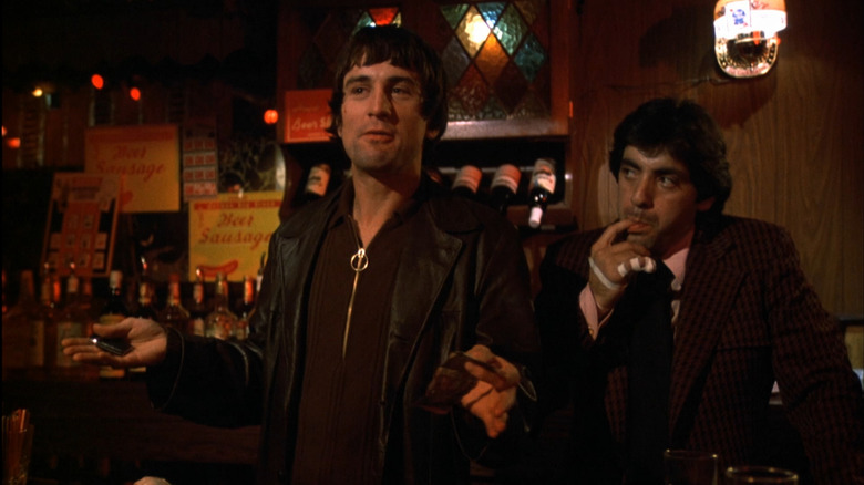 Robert De Niro in the role of Johnny Boy with his hands outstretched in the middle streets