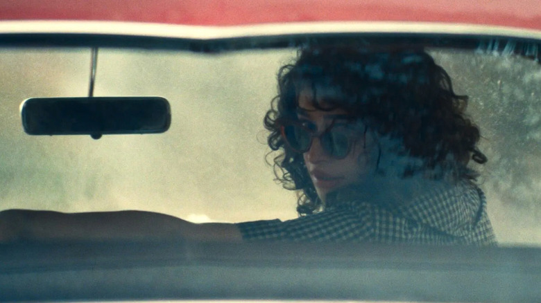 மார்டி சுப்ரீமில் சன்கிளாசுடன் காரின் பின்பக்க ஜன்னல் வழியாக ரேச்சல் (ஒடெசா ஏ'ஸியோன்) பார்க்கிறார்