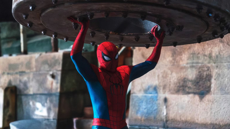 Spider-Man (Tom Holland) holds up a heavy ship part on a dock in Spider-Man: Brand New Day