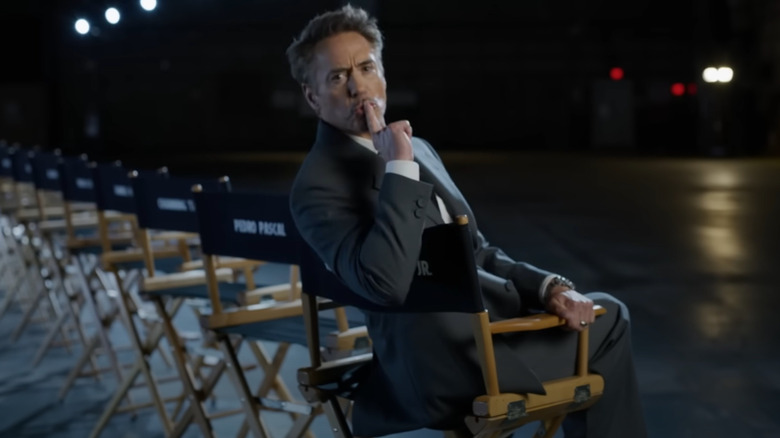 Robert Downey, Jr. making a shushing motion while seated on a chair in a promo for Avengers: Doomsday