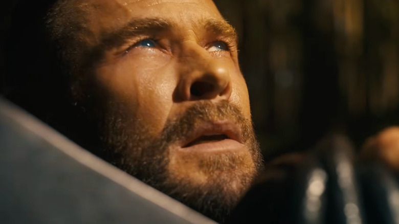 Chris Hemsworth as Thor with his axe and kneeling in a forest in Avengers: Doomsday