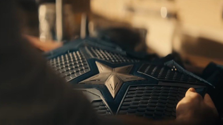 Chris Evans as Steve Rogers holding up his Captain America suit in Avengers: Doomsday