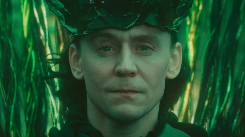 Tom Hiddleston as Loki, sitting on his new throne on Loki Season 2