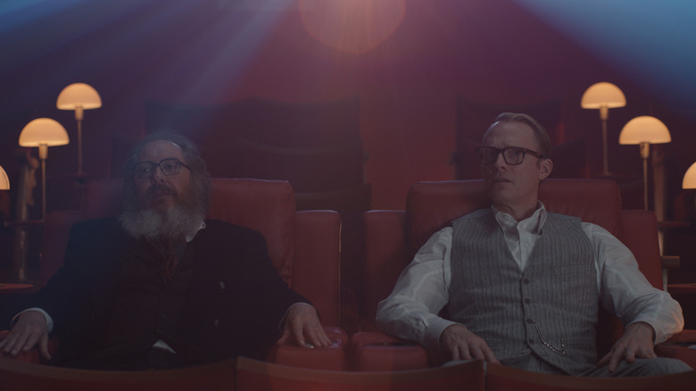 James Spader as Ultron sitting in a small theater next to Paul Bettany as Vision in their human avatars in VisionQuest