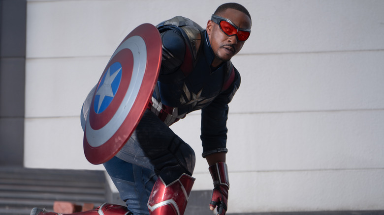 Anthony Mackie like Sam Wilson holding Cape Shield in a squat in Captain America: Brave New World