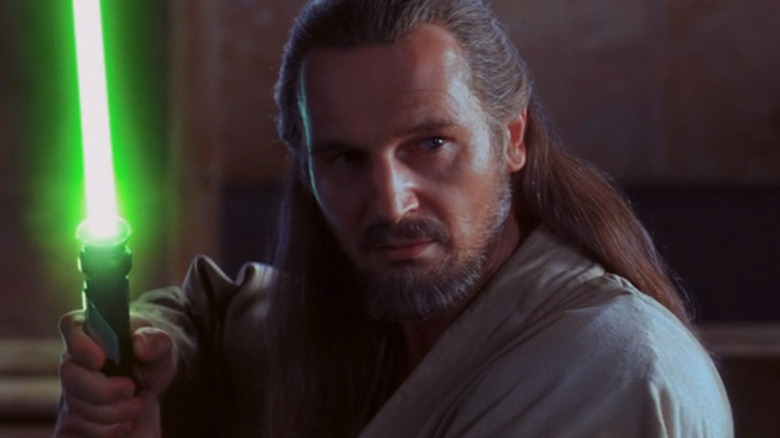 Qui-Gon Jinn segurando o sabre de luz verde em Guerra nas Estrelas: The Phantom Menace