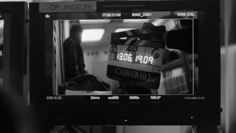 Ablack and white view of a monitor on a film set with a clapperboard labeled Cash Grab 2 in Wonder Man