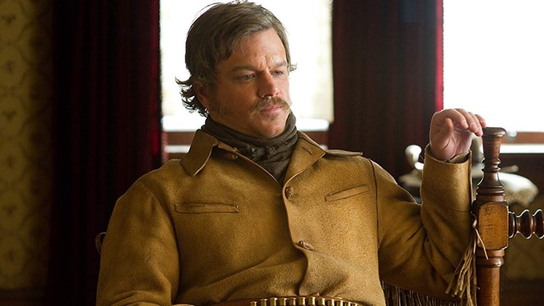 Matt Damon as LaBoeuf sat by a bed in True Grit