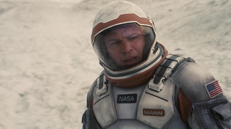 Matt Damon as Dr. Mann stands in a space suit against a bank of snow in Interstellar