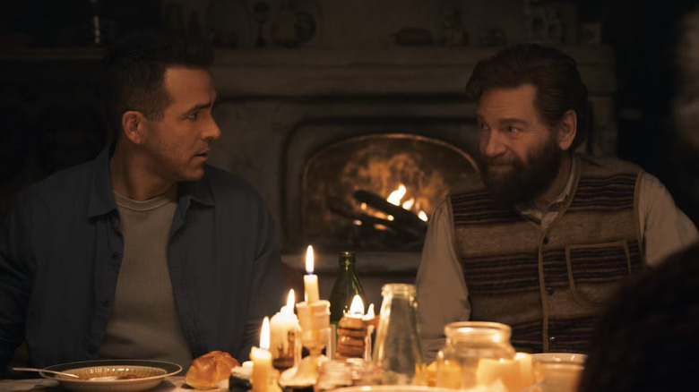 Troy (Ryan Reynolds) and Nikolai (Kenneth Branagh) sit at a family's dinner table in Mayday