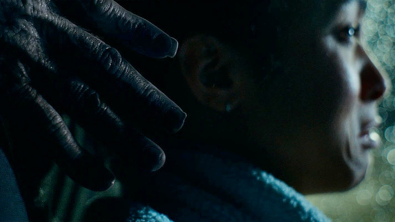Maddie (Lou Llobell) sits in fear as a demonic hand reaches for her in Passenger (2026)