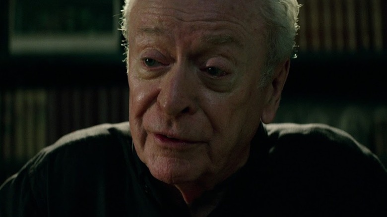 Michael Caine as Dolan sitting at a desk in The Last Witch Hunter