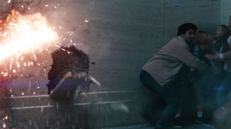 A family cowers in a corner as heat vision destroys a nearby wall in Man of Steel