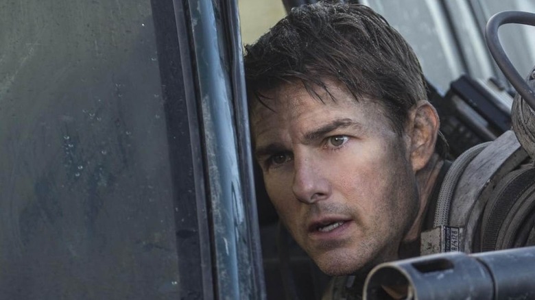 Tom Cruise as Major William Cage leaning against a car