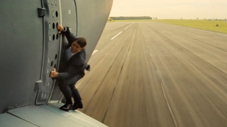 Ethan Hunt (Tom Cruise) hanging from edge of plane in Mission: Impossible - Rogue Nation