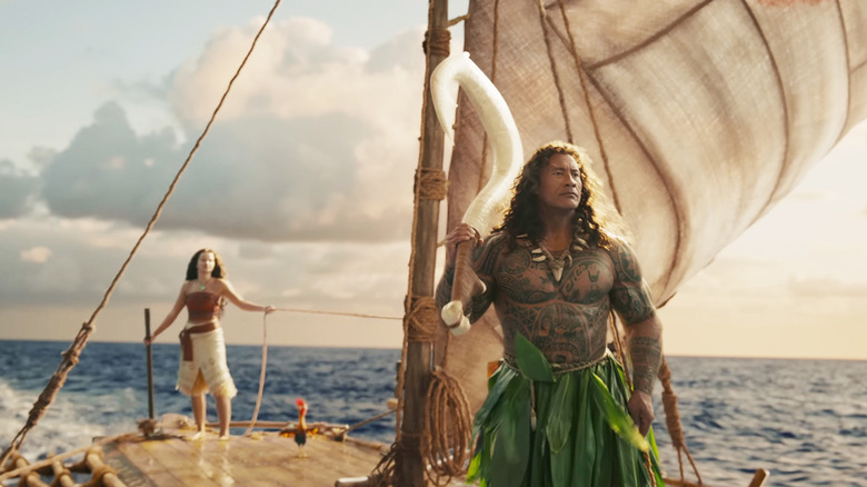 Catherine Laga'aia's Moana stands at the rear of her raft as Dwayne Johnson's Maui stands at the front looking over the ocean in Moana