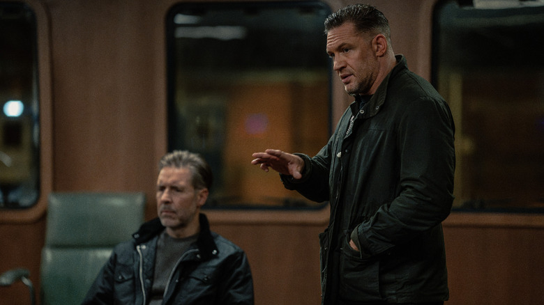 Paddy Considine's Kevin Harrigan sits in a meeting room as Tom Hardy's Harry Da Souza stands next to him in MobLand