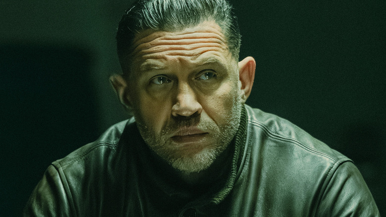 Tom Hardy's Harry Da Souza looks off to his left in a dark room in Mobland