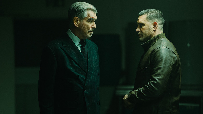 Conrad Harrigan by Pierce Brosnan stands opposite Harry de Souza de Tom Hardy in a dark room in Mobland