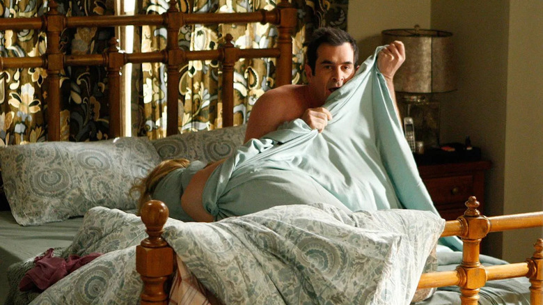 Julie Bowen and Ty Burrell as Claire and Phil, hiding in the covers on Modern Family