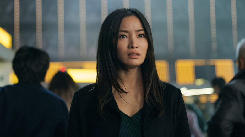 Anna Sawai as Cate Randa wearing black and standing amid a crowd in Monarch: Legacy of Monsters