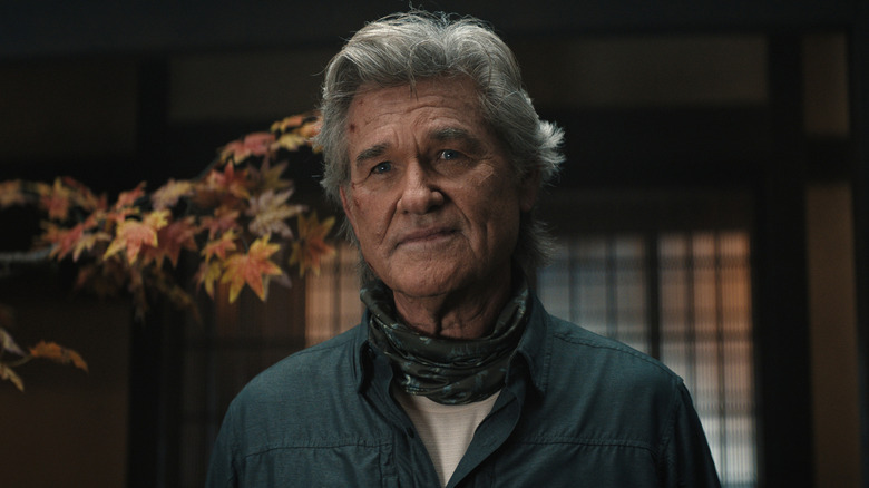 Kurt Russell as Lee Shaw standing in a room with a tree branch in the background in Monarch: Legacy of Monsters