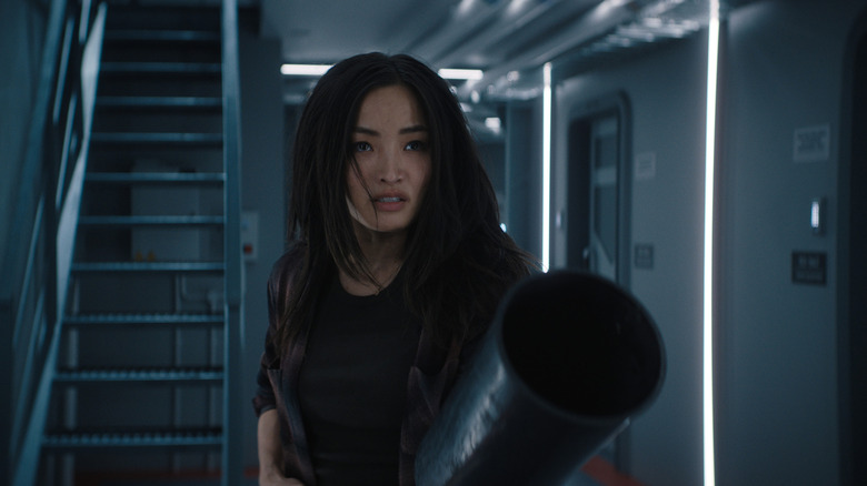 Anna Sawai as Cate Randa holding up a fire extinguisher and staring down an unseen threat in a hallway in Monarch: Legacy of Monsters