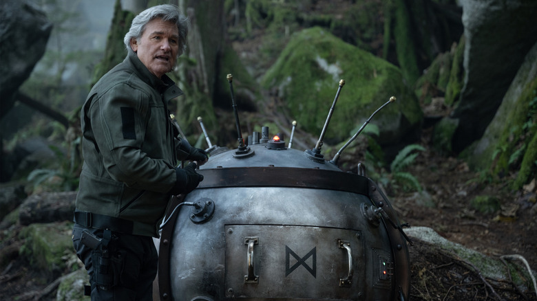 Kurt Russell as Lee Shaw standing in a jungle next to a bomb in Monarch: Legacy of Monsters