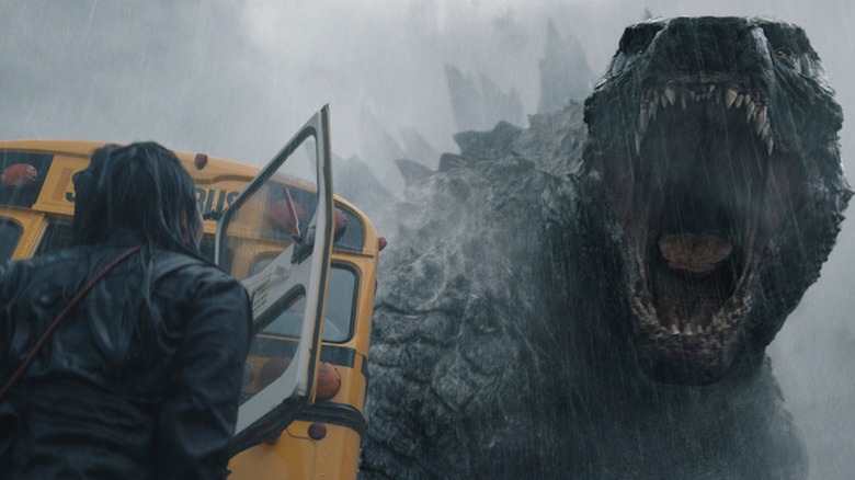 Godzilla unleashes a mighty roar at a human standing next to a school bus in Monarch: Legacy of Monsters