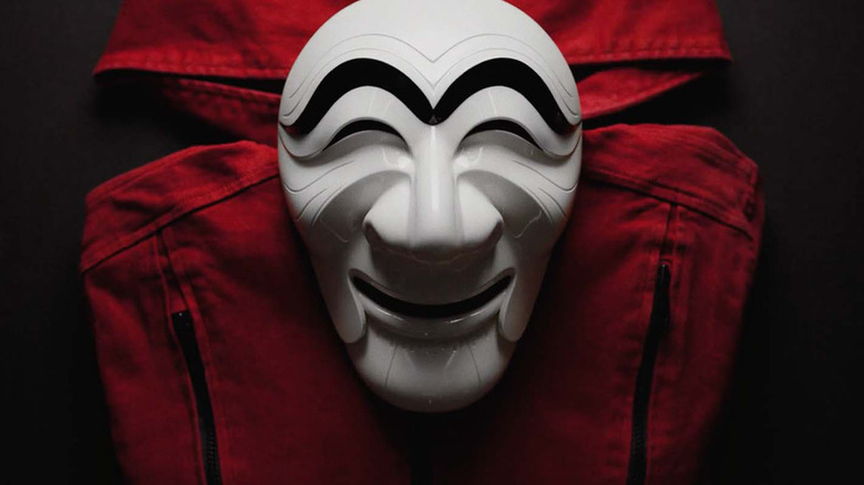 The money heist Korea mask sitting on a red jumpsuit