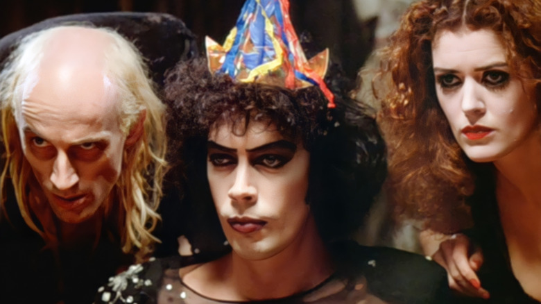 Riff Raff, Dr. Frank-N-Furter, and Magenta glaring across the table in The Rocky Horror Picture Show