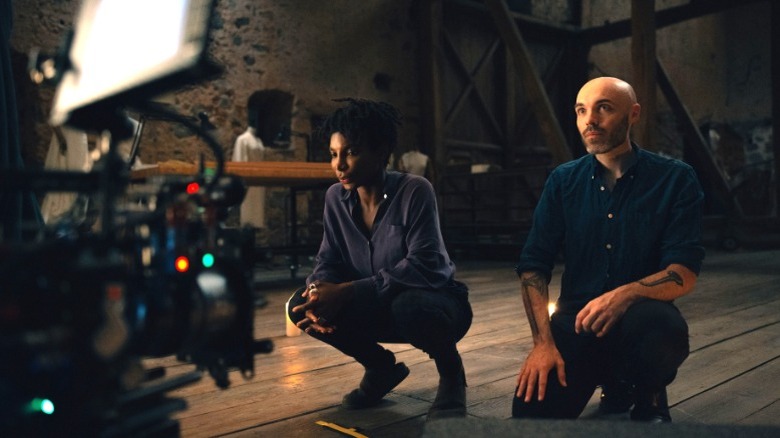 Michaela Coel kneels next to David Lowery on the set of Mother Mary