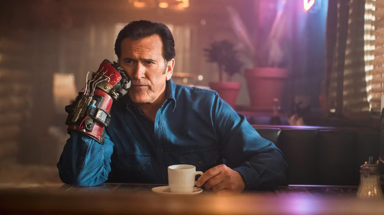 Bruce Campbell as Ash Williams in Ash vs the Evil Dead sitting at a diner table
