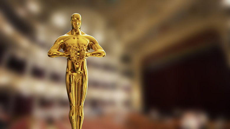 An Oscar statue is seen against a blurry background of a theater