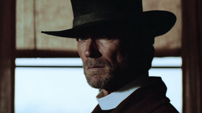 Clint Eastwood's Preacher stands near a door in Pale Rider