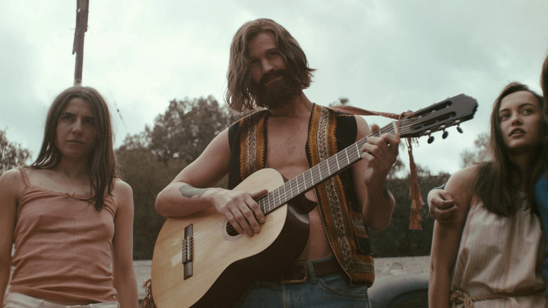 Charles Manson with guitar and followers