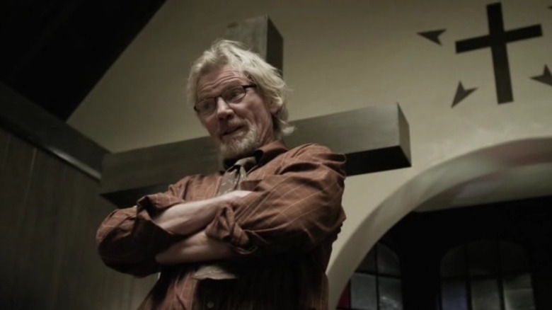 Michael Parks stands in front of a wooden cross