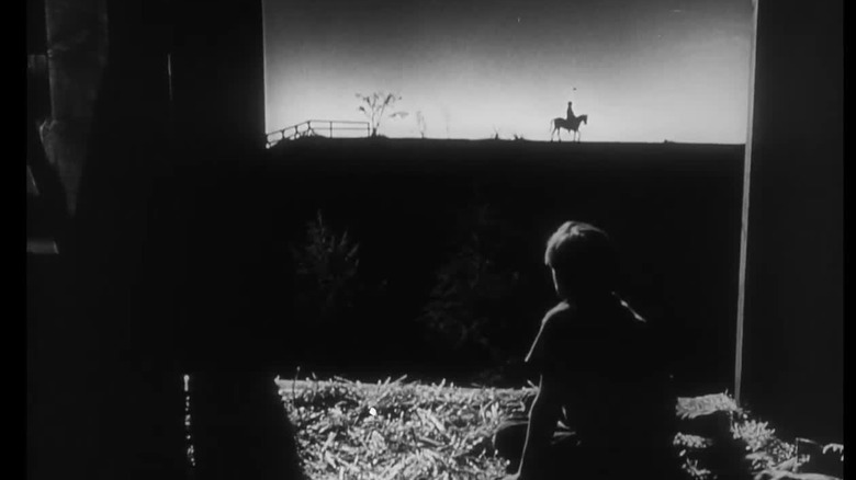 Children watch a priest from a barn
